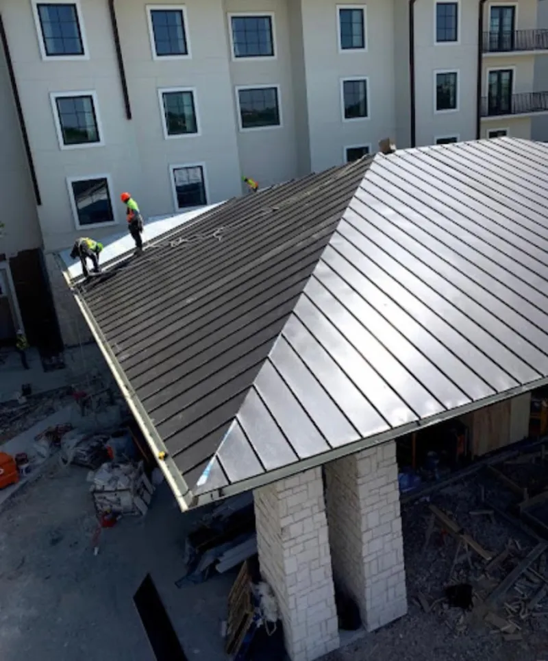 Crew installing standing seam metal roof panels on a commercial project in Miamisburg